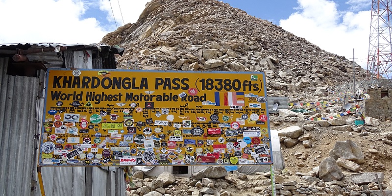 A signboard on Khardung La Pass claiming wrong height. One more thing to note here is unnecessary stickers pasted on the board. 